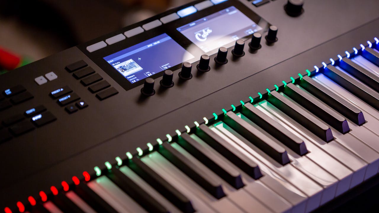 who-we-are Close-up of an electronic keyboard with colorful illuminated keys in a studio setting.